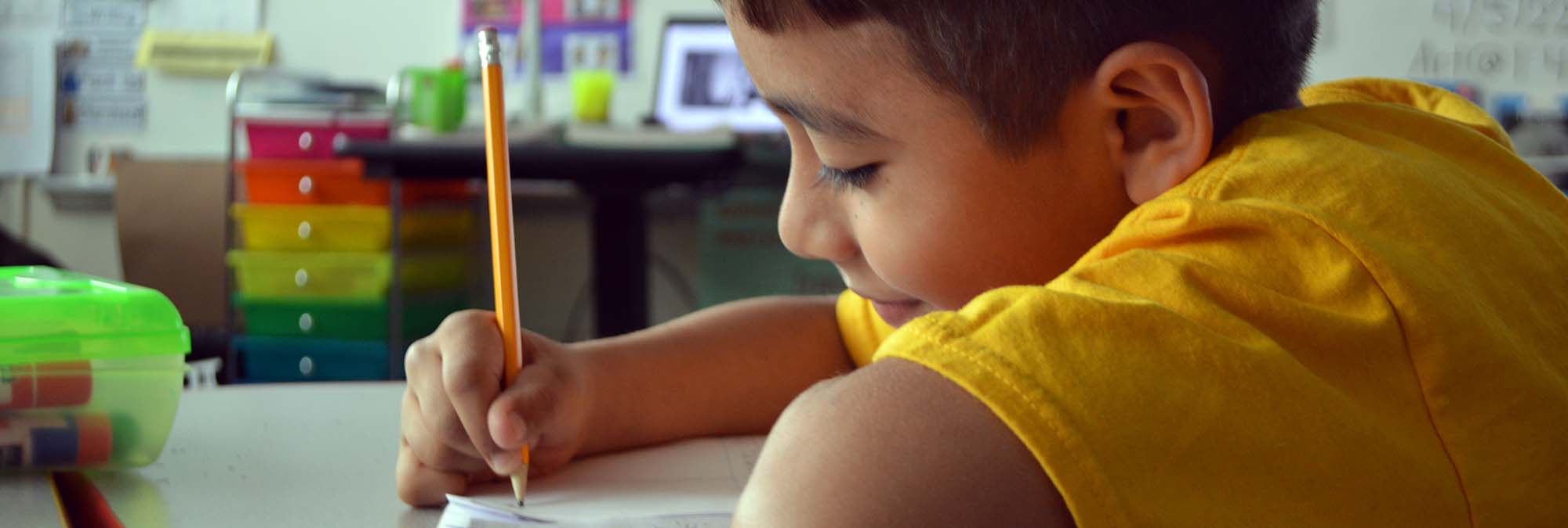 Student writes with a pencil in classroom