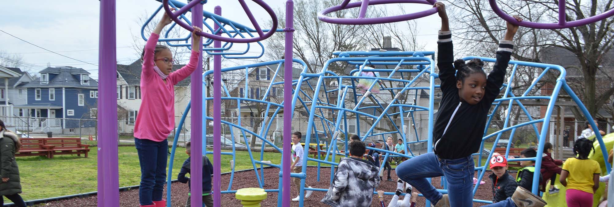 Students use monkey bars on playground at recess