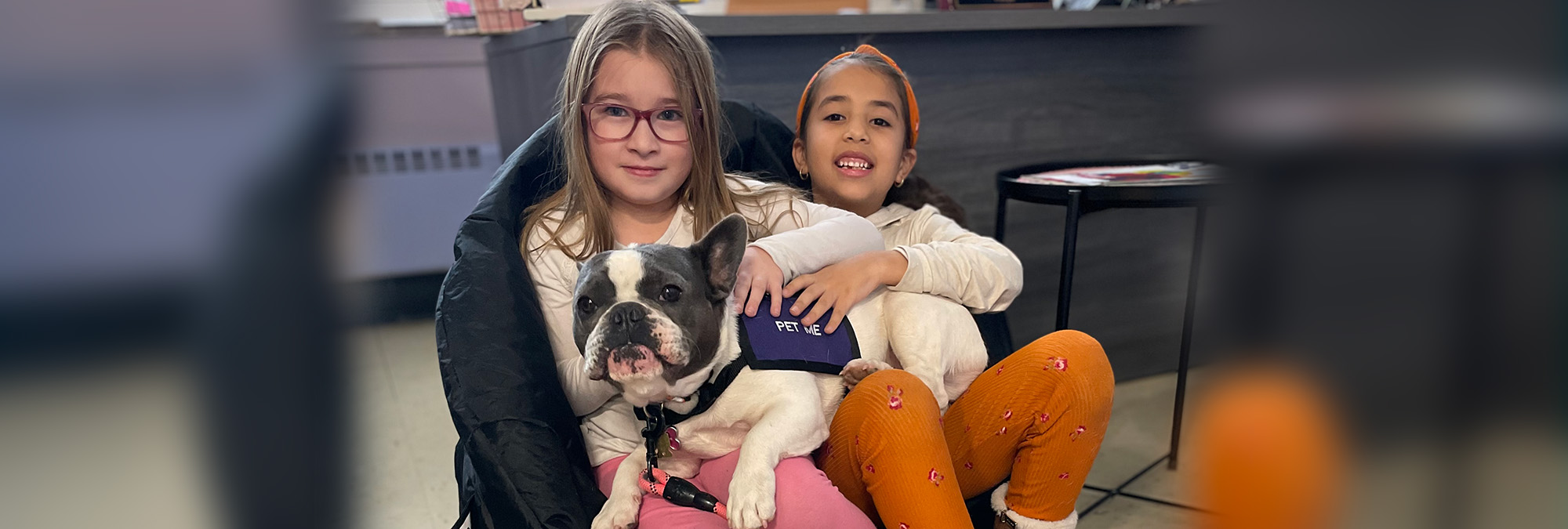  Two students sitting with a therapy dog on their laps